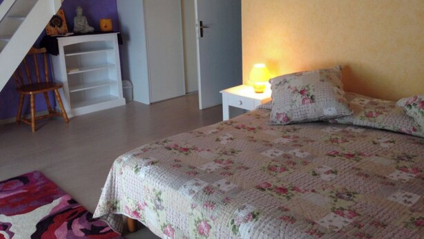 A bedroom with a bed, a nightstand, a chair, a staircase, and a door. - Holistic Retreat in the foothills of French Pyrenees (Bonnac)