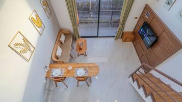 A modern living room with a wooden dining table, sofa, and TV.