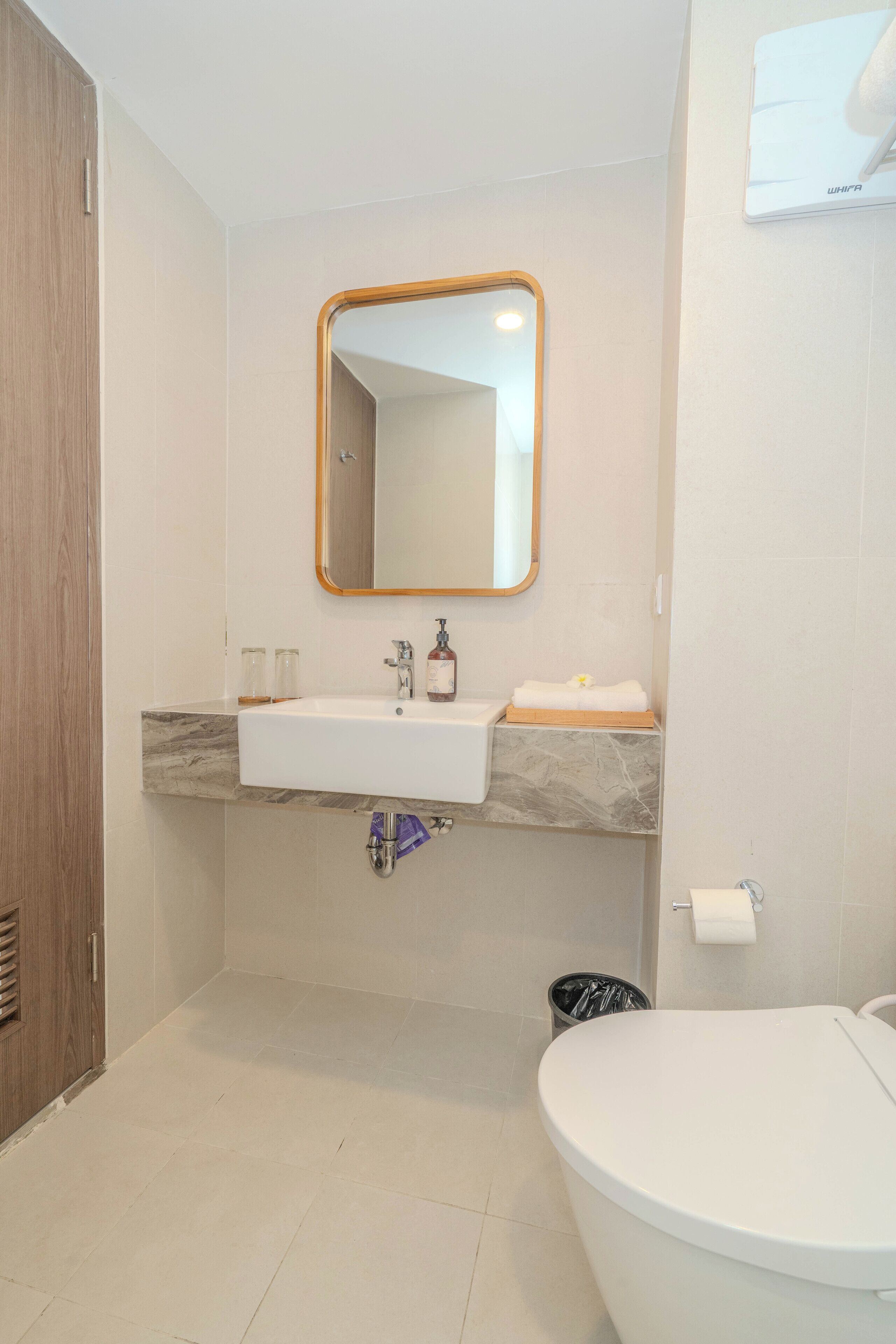 Un baño con lavamanos, espejo y retrete blancos.