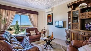 A spacious living room with leather sofas, a coffee table, and a TV.