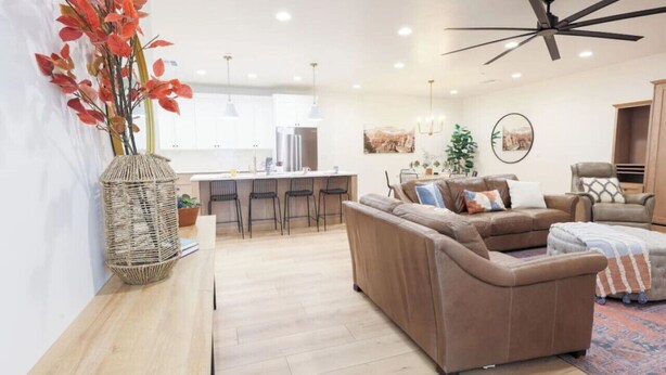 Een moderne woonkamer met een bank, een houten tafel en een keuken op de achtergrond.