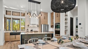 A modern kitchen with wooden cabinets, a central island, and a dining area set for six.