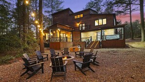 Une cabane en rondins moderne dotée d’une terrasse, d’un espace salon extérieur et d’un foyer.