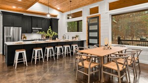 Une cuisine moderne dotée d’un îlot central, de tabourets de bar et d’une table à manger avec des chaises.