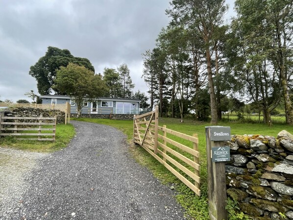 A gravel path leading to a cottage with a wooden gate and a stone wall. - Swallows Lodge - Modern accommodation with breathtaking views (Keswick)