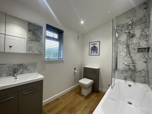A modern bathroom with a marble backsplash, a freestanding bathtub, a toilet, and a vanity with a mirror. - Swallows Lodge - Modern accommodation with breathtaking views (Keswick)