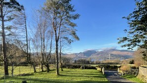 A grassy field with trees and a stone wall, leading to a stone bridge over a stream. - Swallows Lodge - Modern accommodation with breathtaking views (Keswick)