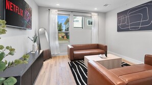Un salon moderne avec un canapé en cuir, une table basse et un téléviseur à écran plat fixé au mur.