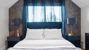 Une chambre à coucher avec un grand lit, des rideaux foncés et deux lampes de chevet.