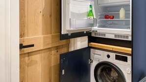 Une cuisine compacte dotée d’un réfrigérateur et d’un lave-linge intégrés.