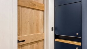 Une porte en bois avec une poignée en métal et une porte bleu foncé avec deux poignées et une petite grille carrée.