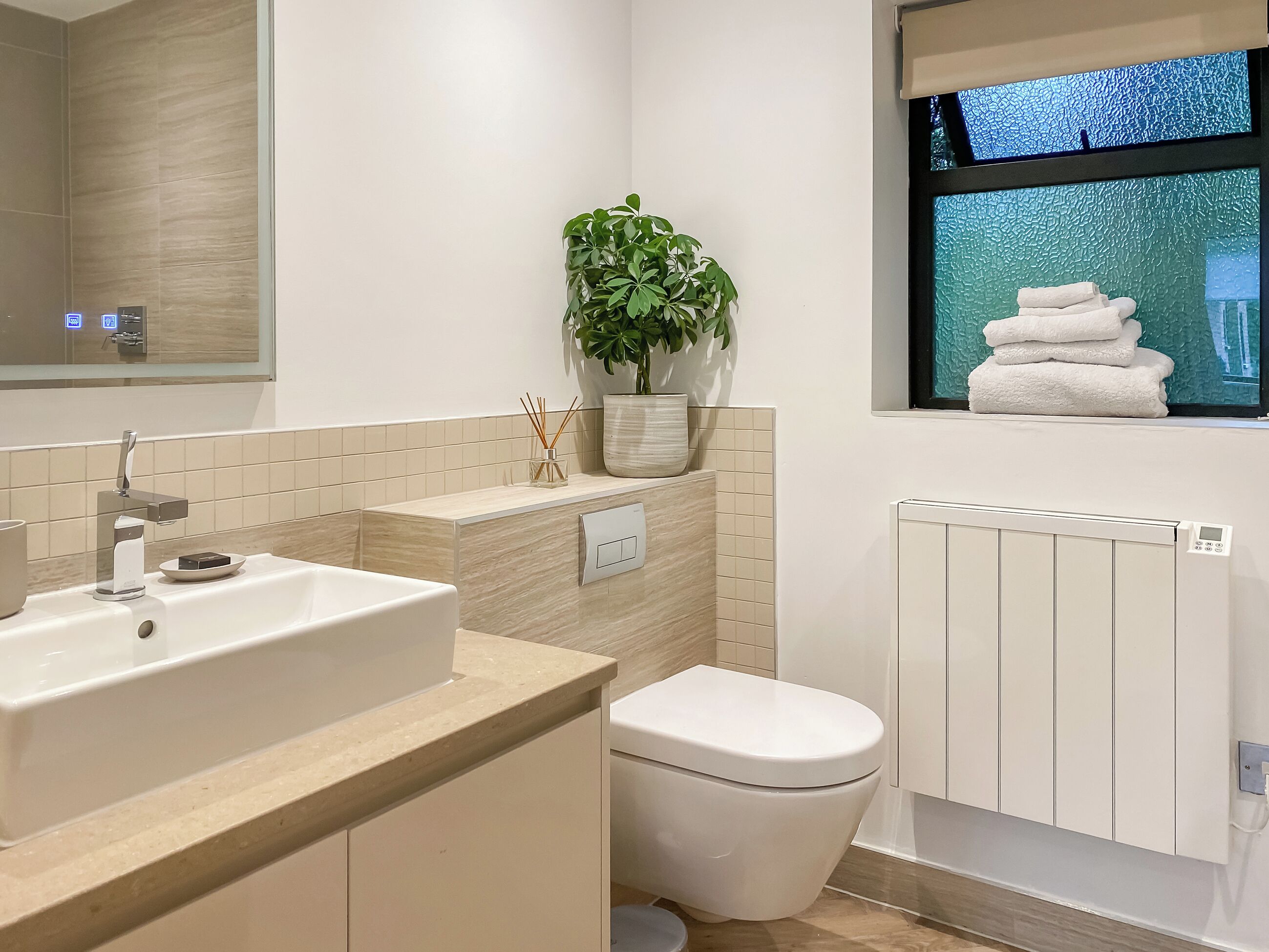 Une salle de bain moderne avec un lavabo, des toilettes et une fenêtre avec des serviettes.