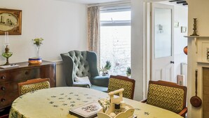 Ein Essbereich mit einem runden Tisch, Stühlen, einer Chandelier und Blick ins Freie.