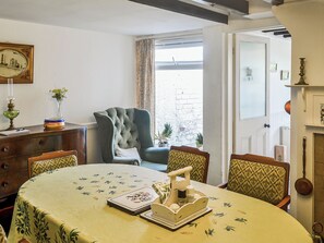 En spiseplads med et rundt bord, stole, en lysekrone og udsigt udad.