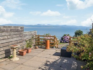 En terrasse med plantekasser, et træhegn og havudsigt.