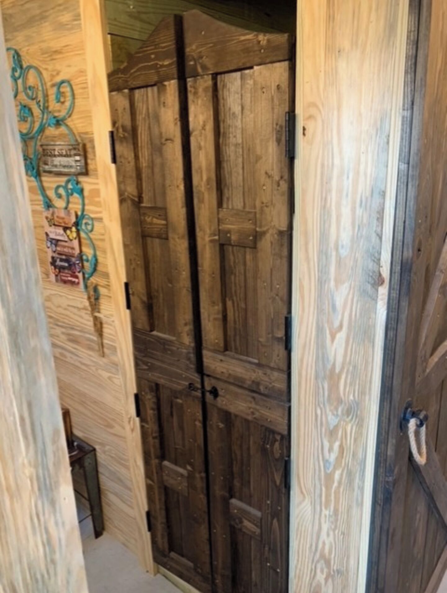 A wooden door with a rustic design, a small shelf with various items, and a metal handle.