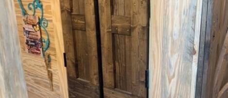 A wooden door with a rustic design, a small shelf with various items, and a metal handle.