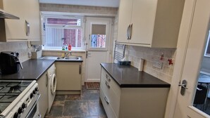 Een kleine keuken met een gasfornuis, een wasmachine en een spoelbak.