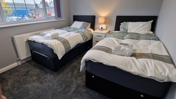 Hotelkamer met twee bedden, een raam met uitzicht, een nachtkastje met lamp en een radiator.