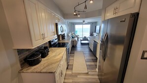 A modern kitchen with white cabinets, a built-in oven, and a stainless steel refrigerator.
