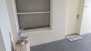 A room with a large window, a welcome mat, and a decorative dolphin sculpture on a textured stool.