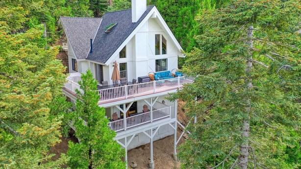 A two-story house with a balcony, surrounded by dense forest.