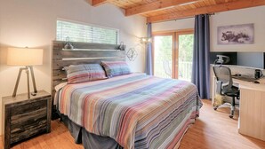 A bedroom with a bed, a desk, and a computer setup.