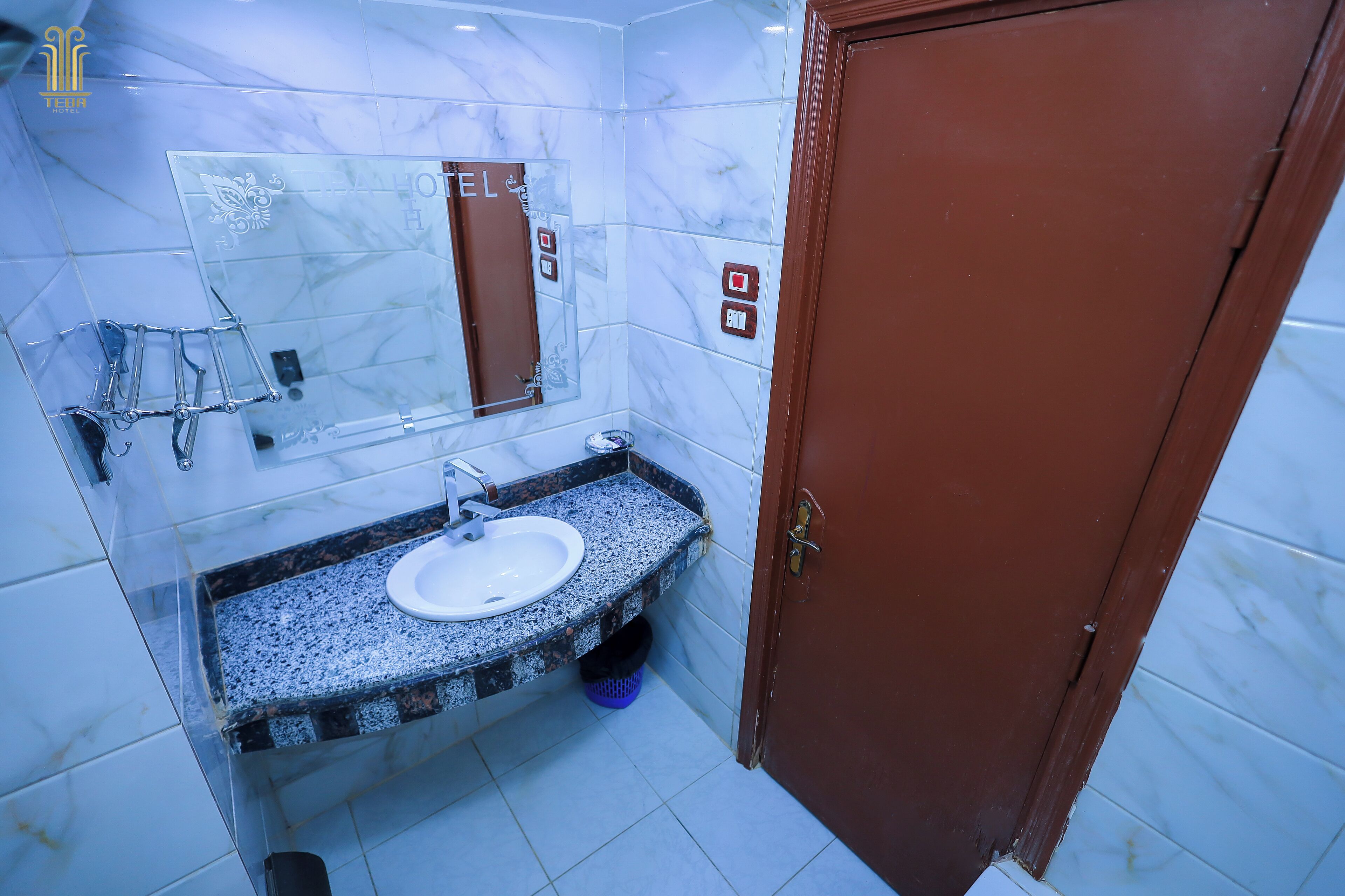 A bathroom with a marble wall, a sink with a mirror, and a door.