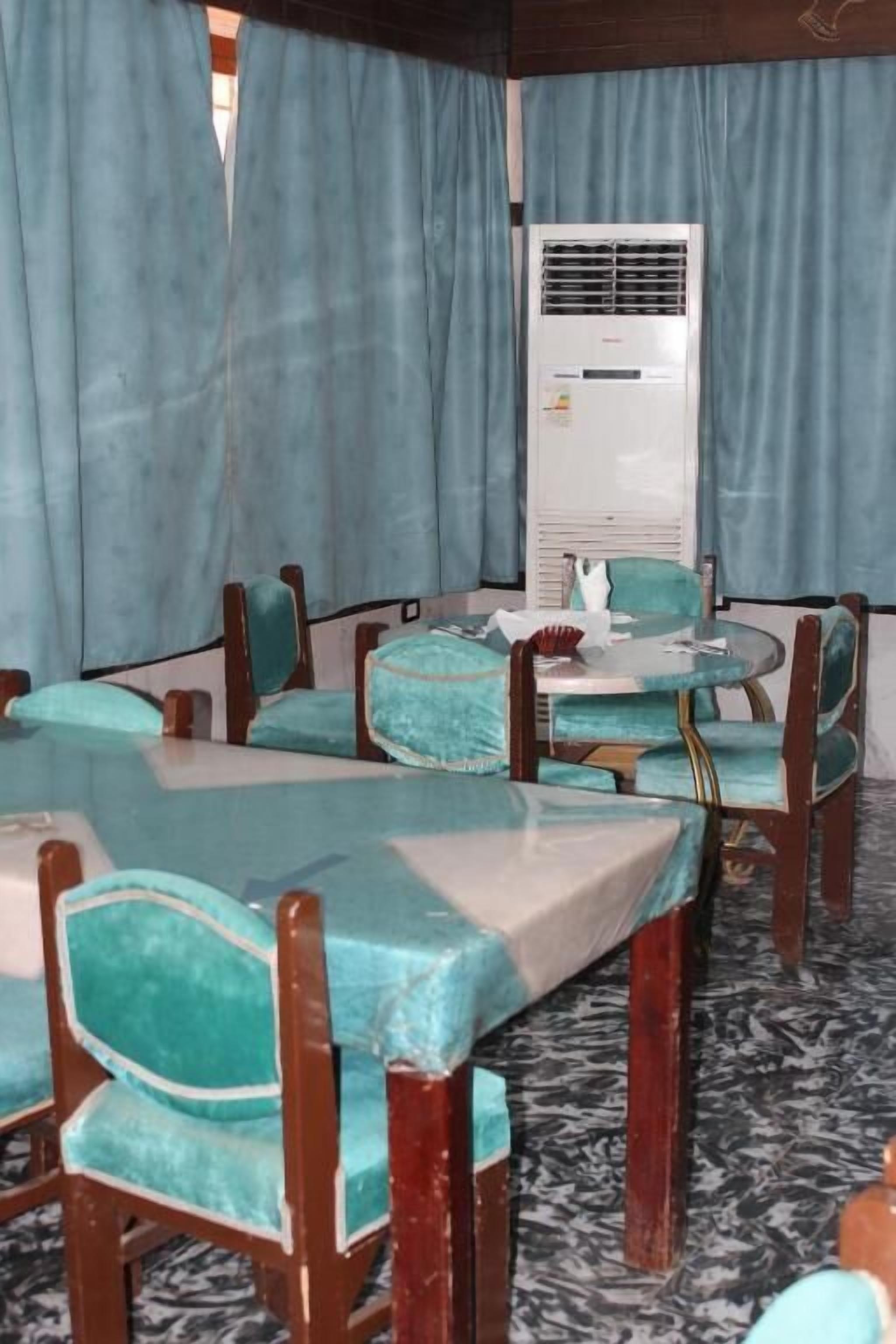 A dining area with round tables and chairs, an air conditioning unit, and curtains.