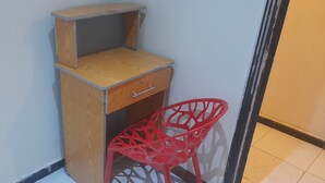 Un coin avec un meuble en bois doté d’un tiroir et d’une chaise rouge.