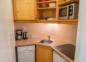 A compact kitchen with a sink, a microwave, a coffee maker, and a dishwasher.