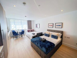 Habitació d'hotel moderna amb un llit gran, un escriptori i zona de menjador.