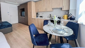 Eine moderne Küche mit Holzausstattung, ein Essbereich mit blauen Stühlen und ein kleiner Tisch für zwei Personen.