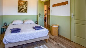 A bedroom with a bed, pillows, a bedside lamp, a waste basket, and a door. - Villa Du Soleil by Villa Plus (Laroque-des-Albères)