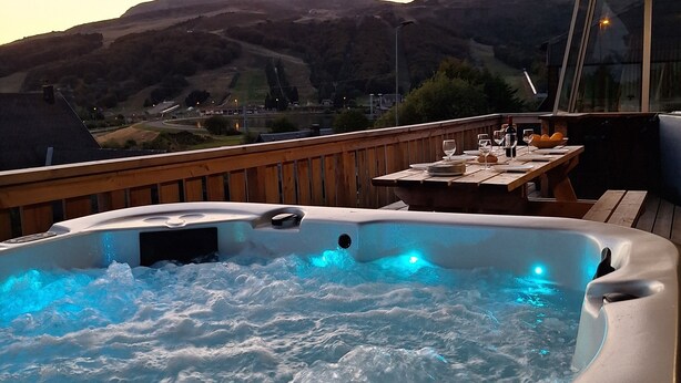Un jacuzzi con cubierta de madera y vista a un paisaje montañoso.
