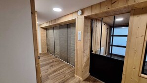 Un pasillo con paneles de madera y un electrodoméstico negro, posiblemente un refrigerador, a la derecha.