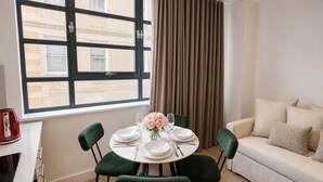 Un comedor con una mesa redonda, sillas verdes y un sofá blanco.