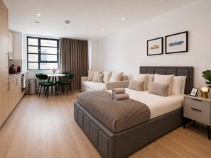 Een moderne slaapkamer met een groot bed, een bank, een eethoek en een keuken.