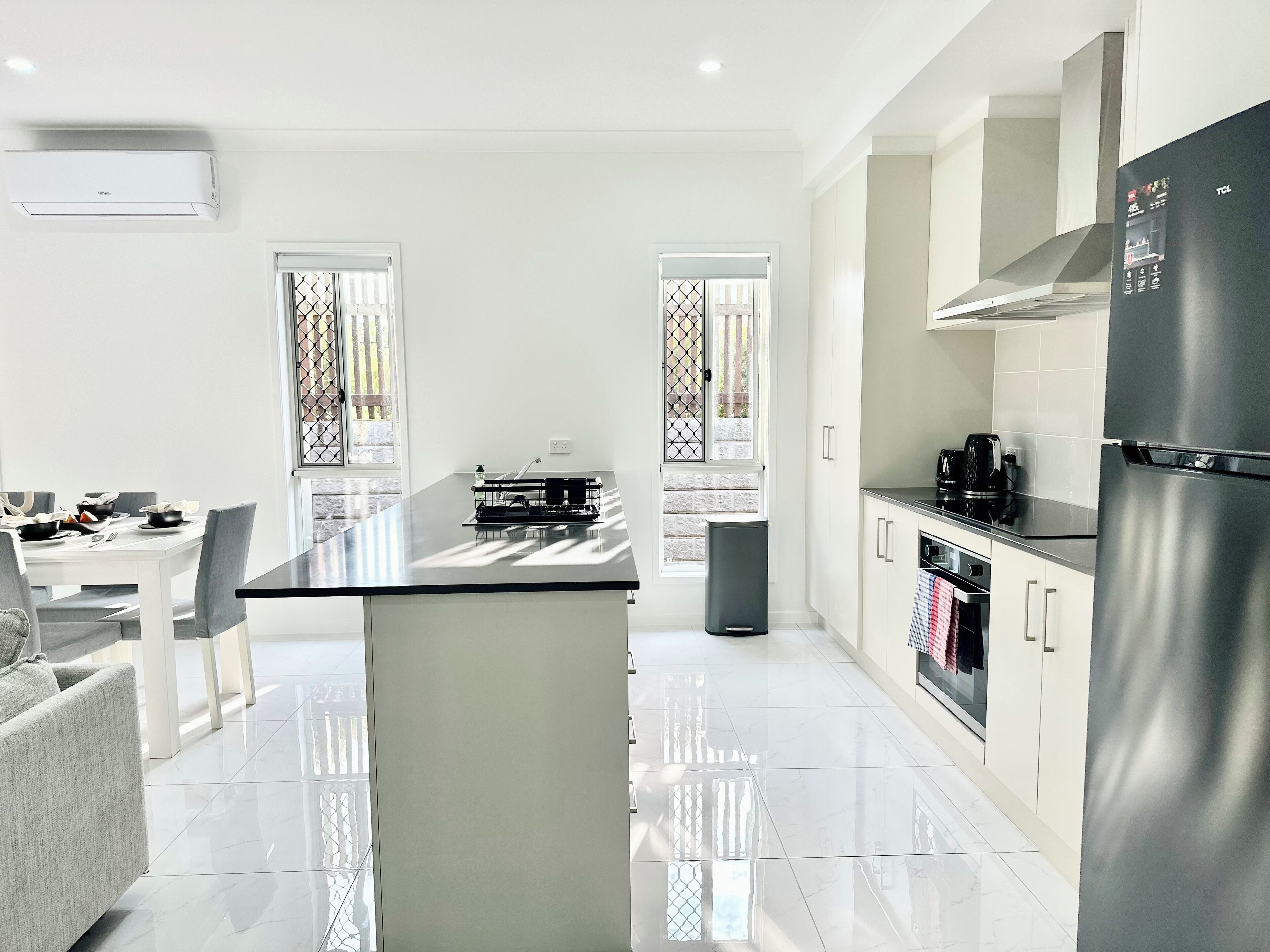A modern kitchen with a central island, stainless steel appliances, and a dining area with a table and chairs.