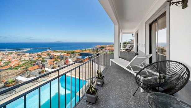 A balcony with a pool, chairs, and potted plants. - São Lourenço Guest House (Machico)