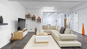 A modern living room with a sectional sofa, a coffee table, a TV, and a fireplace. - São Lourenço Guest House (Machico)