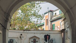 An outdoor courtyard with a tiled floor, a yellow table, and a door leading to a building. - Casa Lena B&B (Naples)
