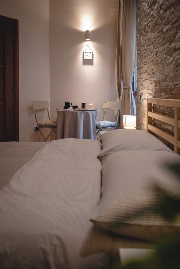 A cozy bedroom with a large bed, a small table with a lamp, and a wall-mounted light fixture. - Casa Lena B&B (Naples)