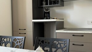 Een moderne keuken met een marmeren aanrecht, een koffiezetapparaat en een dienblad met theekoppen en een theepot.