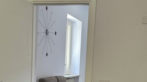 Een kamer met een grijze bank, een bureau met een stoel, en een radiator.
