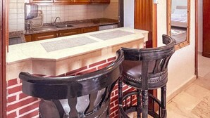 A kitchen with wooden cabinets, a countertop, and two black bar stools. - ZAYANE HOMES AGADIR (Agadir)