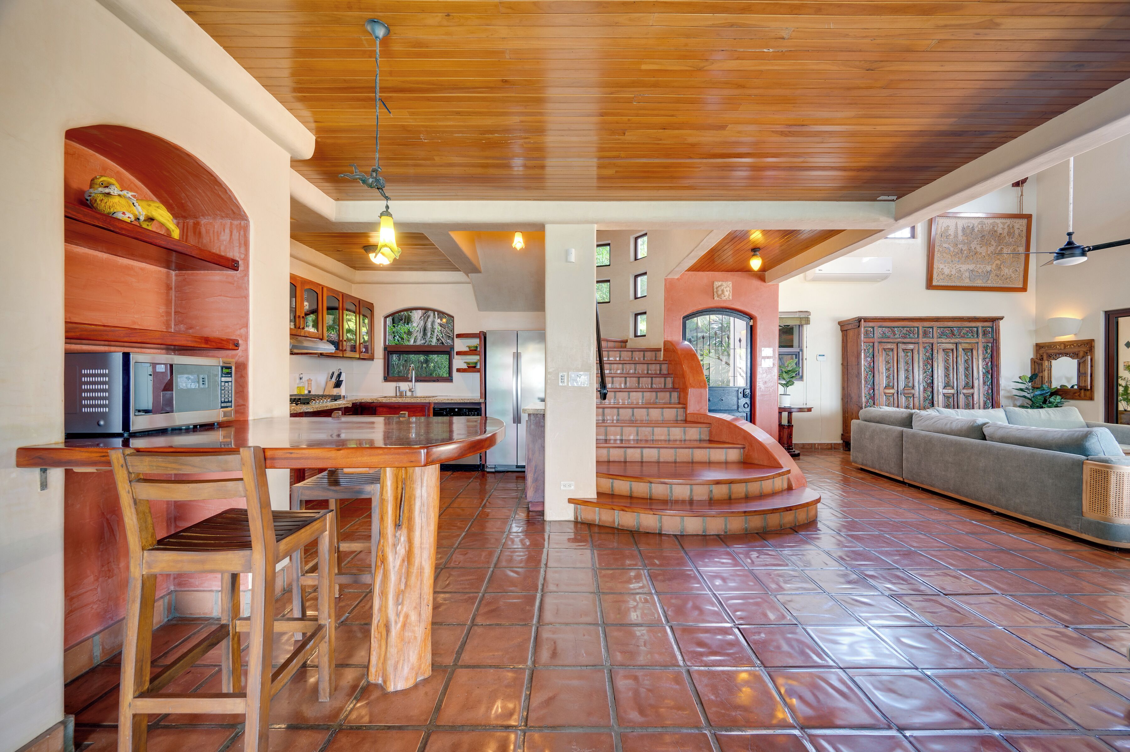 A spacious living area with a wooden staircase leading to a loft, a kitchen with modern appliances, and a cozy seating area.