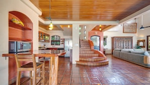 A spacious living area with a wooden staircase leading to a loft, a kitchen with modern appliances, and a cozy seating area. - Enchanting 6 Bedroom Villa with Incredible Views- Fully Staffed -Walk to Beach (Tamarindo)