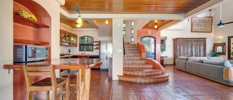 A spacious living area with a wooden staircase leading to a loft, a kitchen with modern appliances, and a cozy seating area.