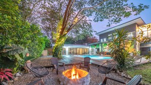 Ein Garten mit Feuerstelle, Sitzgelegenheit und Schwimmbecken.